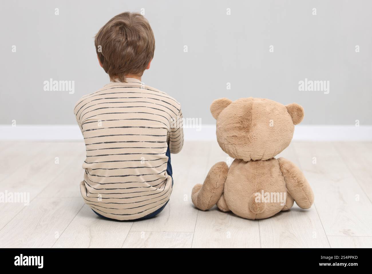 Autism concept. Lonely little boy with teddy bear on floor at home ...