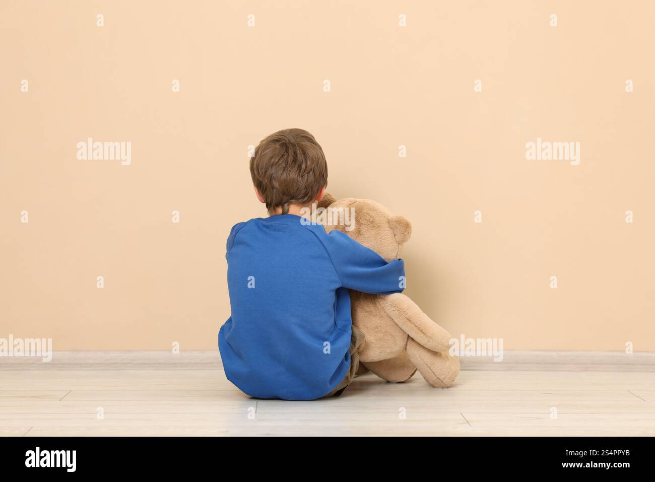 Autism concept. Lonely little boy with teddy bear on floor at home ...