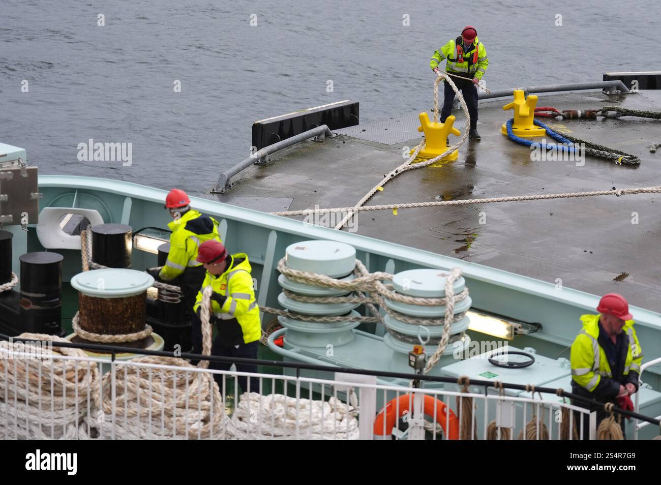 Workers pull ropes on board The Glen Sannox ferry ahead of departing