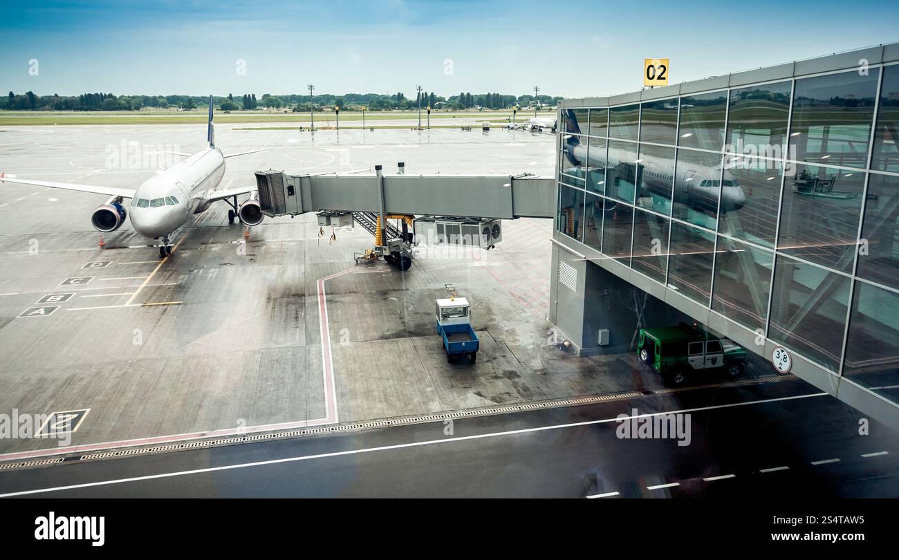 Big airliner parked next to boarding gate in airport terminal Stock Photo