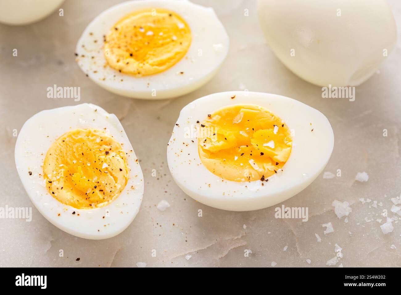 Soft boiled eggs cut in half with salt and black pepper Stock Photo