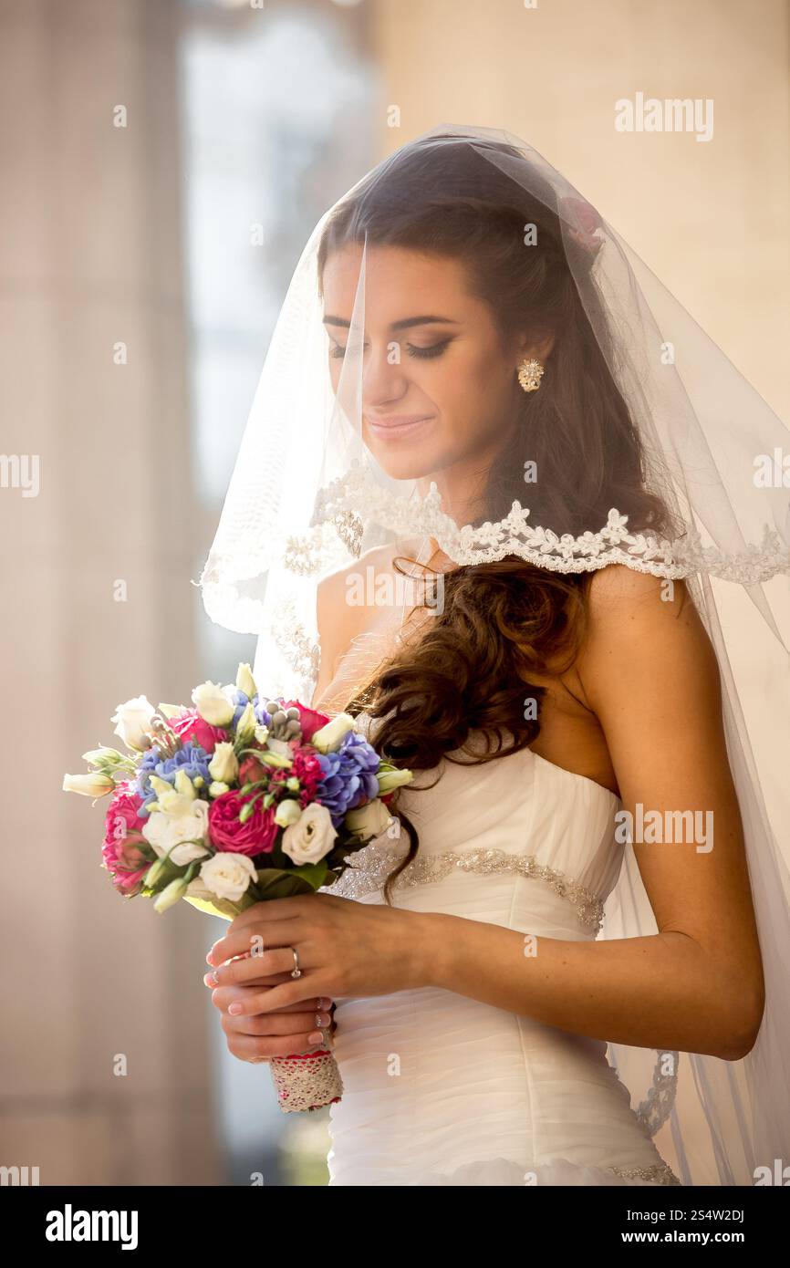 Closeup portrait of cute brunette bride with wedding bouquet at sunny day Stock Photo
