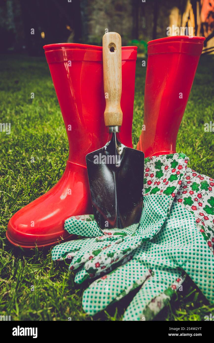 Closeup toned filter of garden tools and red boots on meadow Stock Photo