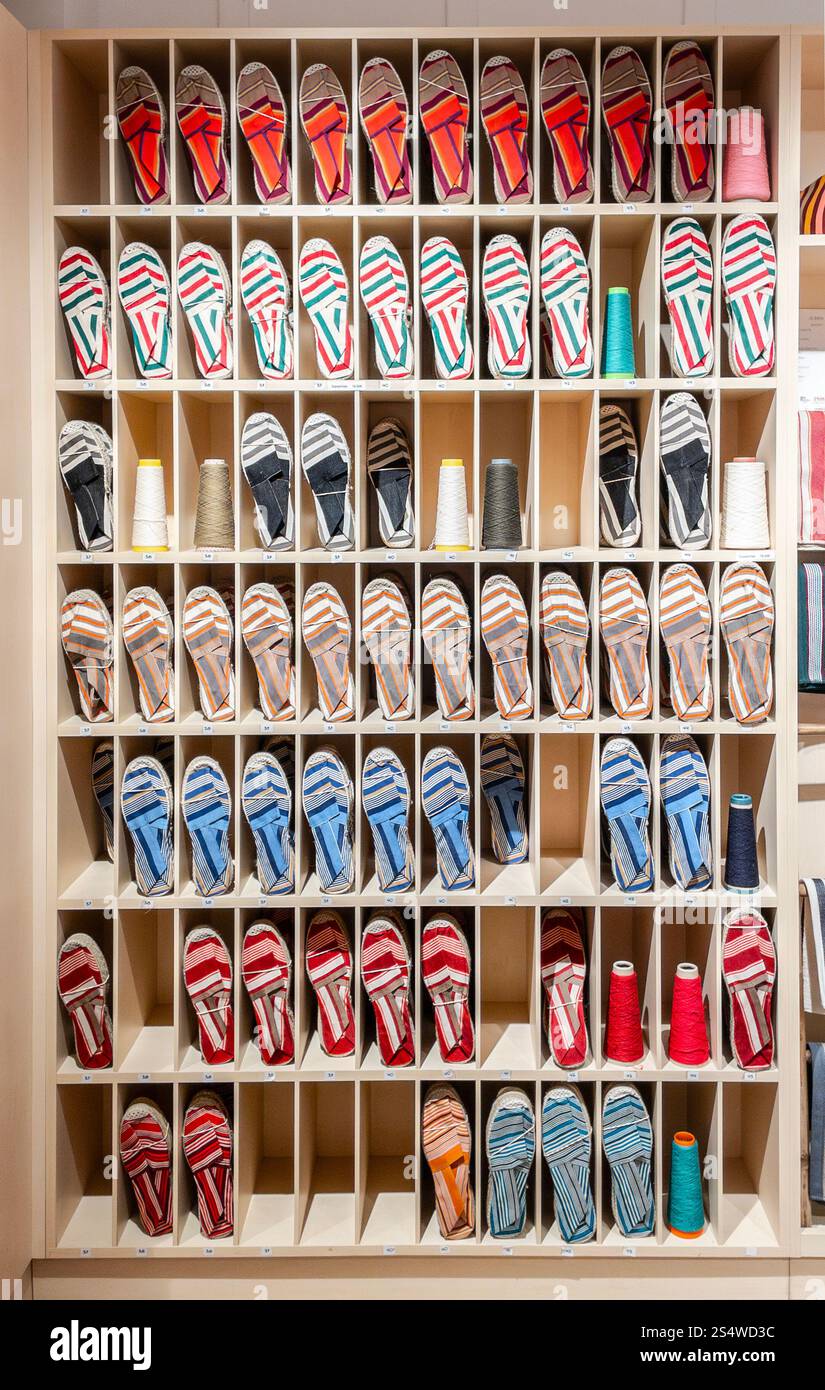 A display of colorful Espadrilles arranged neatly in wooden cubbyholes at a store. Stock Photo