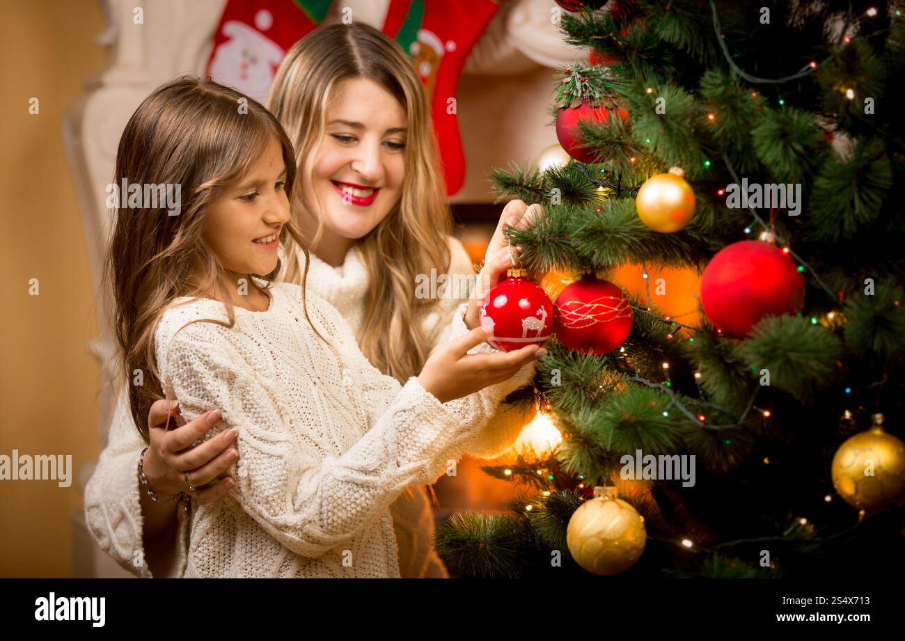Portrait of smiling mother decorating Christmas tree with daughter Stock Photo