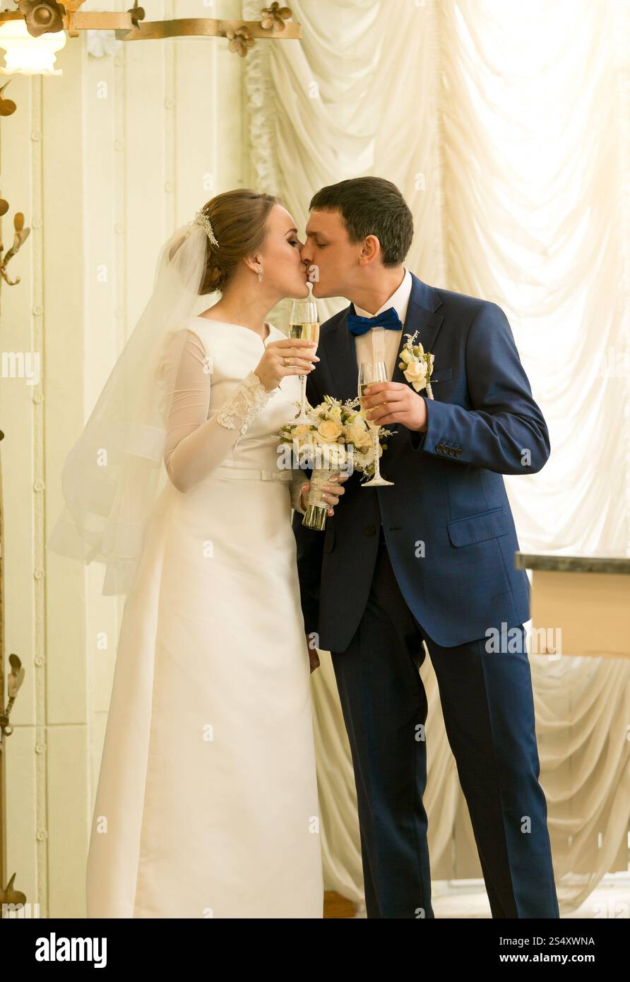 Toned portrait of beautiful newly married couple kissing in luxurious hall Stock Photo