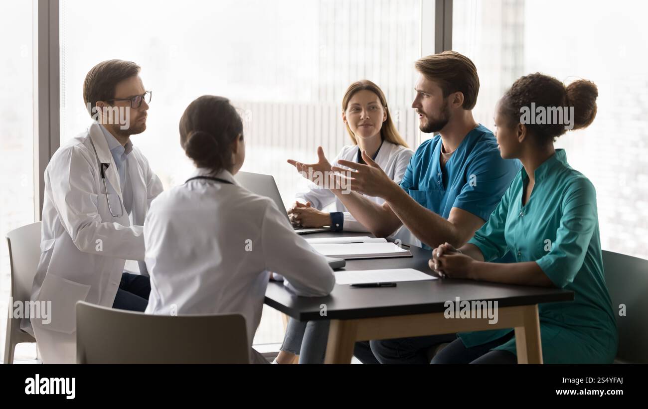 Young doctor make speech during briefing with diverse clinic workmates Stock Photo