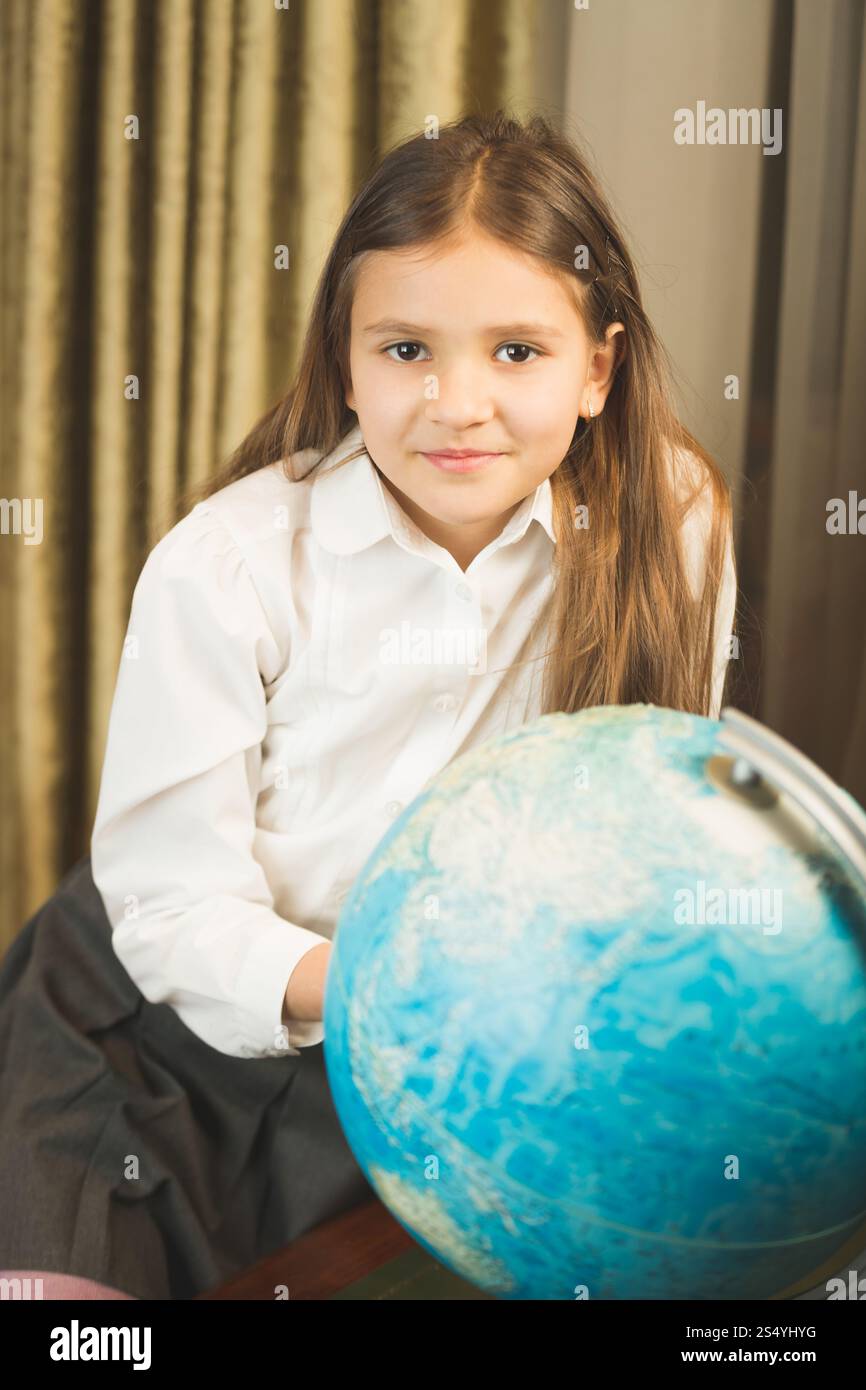 Portrait of smiling schoolgirl posing with Earth globe at cabinet Stock ...