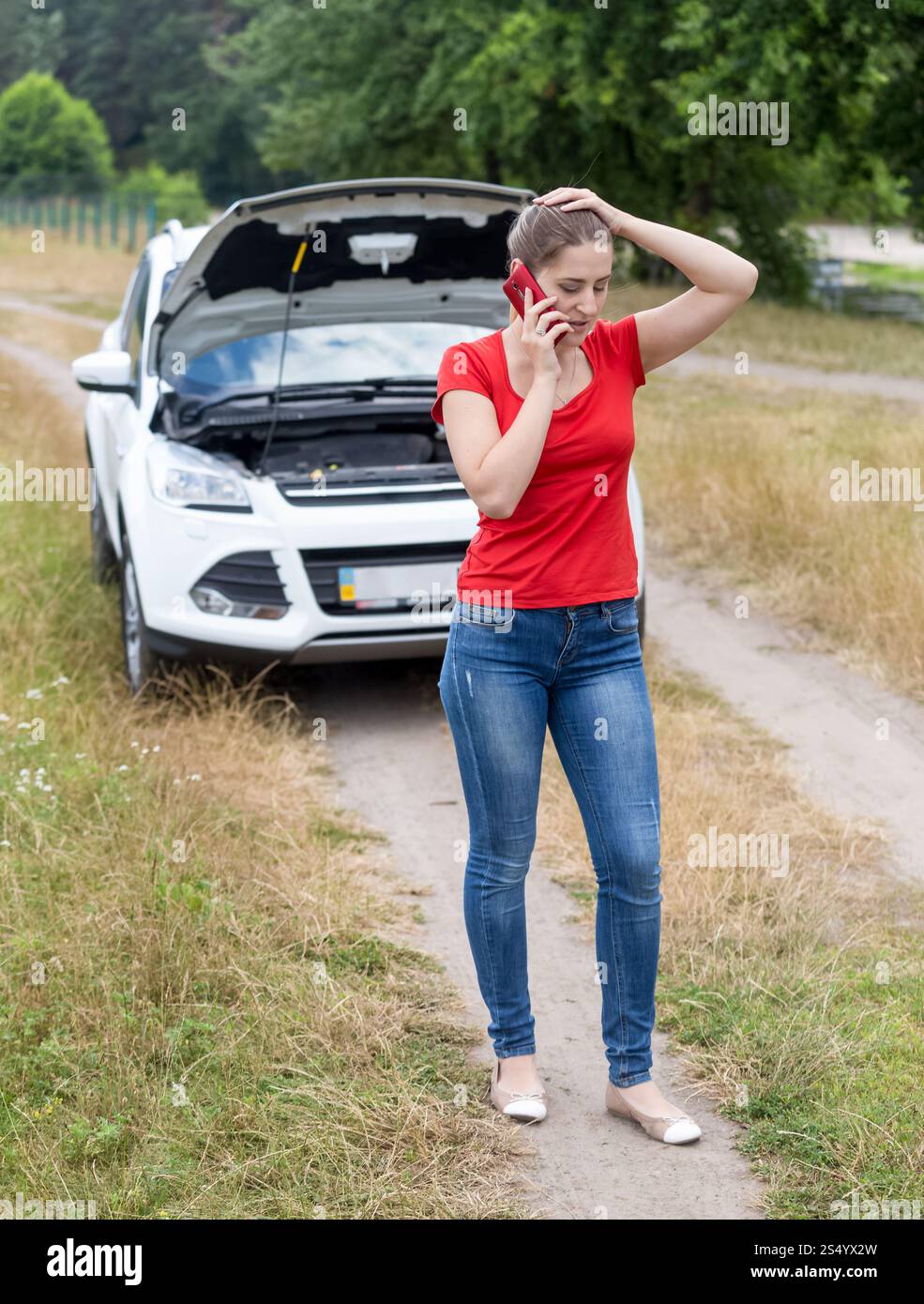 Frustrated woman calling for help with her broken car at rural road Stock Photo