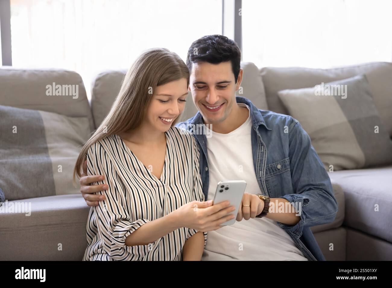Positive Latin husband and wife using application on mobile phone Stock Photo