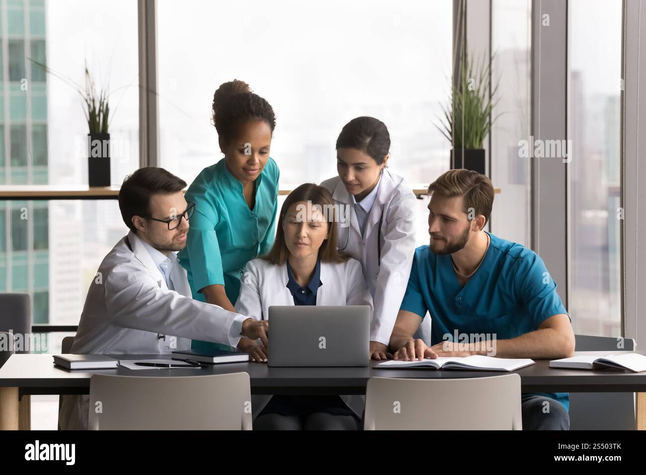 Five professional medical workers working together using laptop Stock Photo