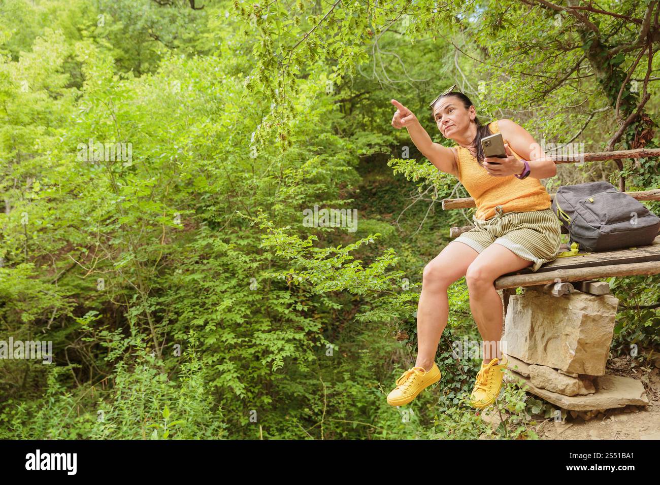 Woman using smartphone for pathfinding in forest Stock Photo