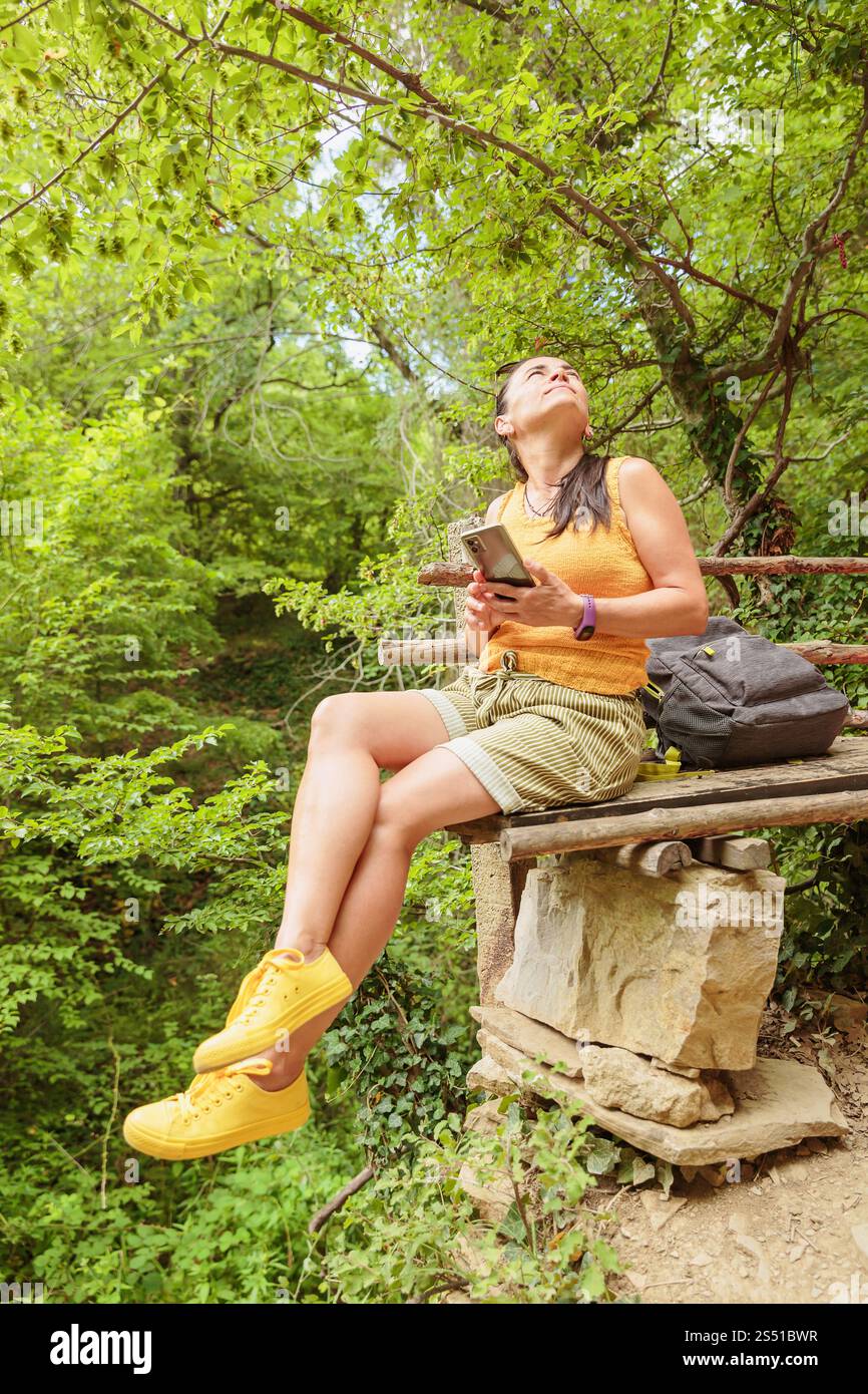 Woman using smartphone for pathfinding in forest Stock Photo