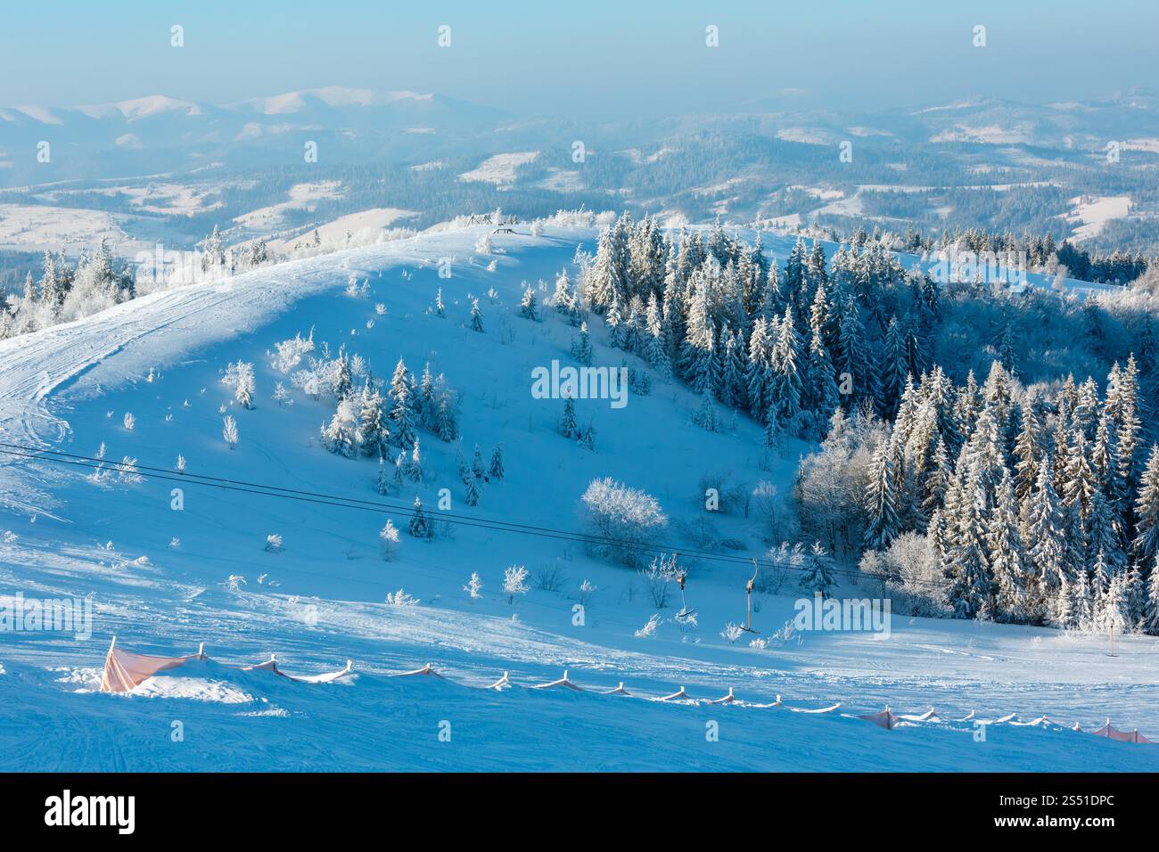 Morning winter calm mountain landscape with beautiful frosting trees in mountains shadows and ski slope (Carpathian Mountains, Ukraine). Winter Stock Photo