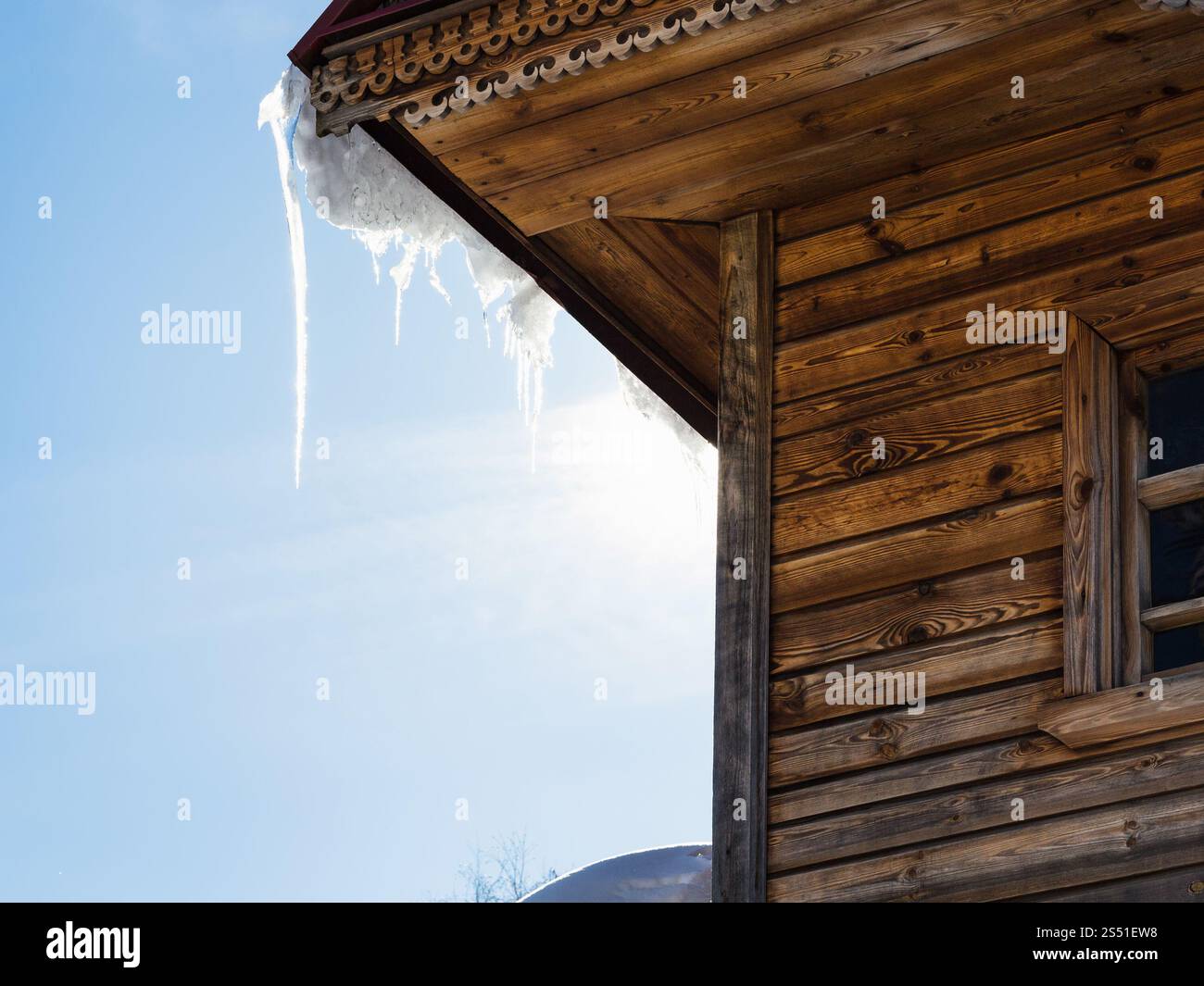 icicle illuminated by sun on roof of old log house. icicle illuminated by sun on roof of old log house in Suzdal town in spring in Vladimir oblast of Stock Photo