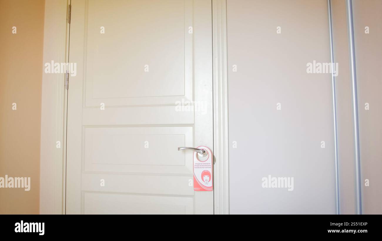 Red do not disturb sign hanging on wooden door at hotel. Do not disturb ...