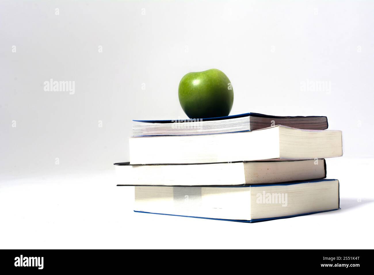 Pile of books with green apple white background Stock Photo