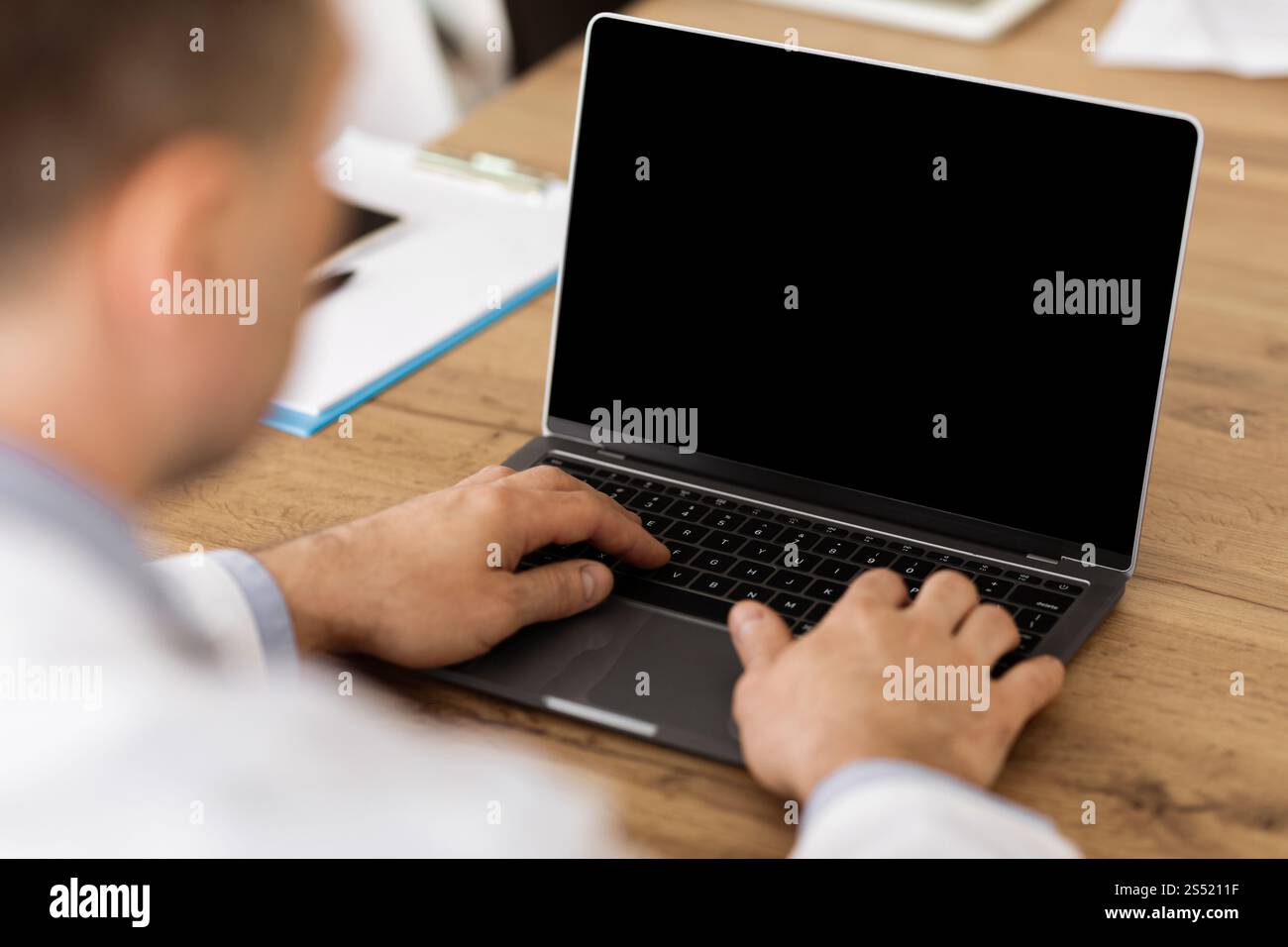 Man working on laptop with empty black screen for mockup Stock Photo