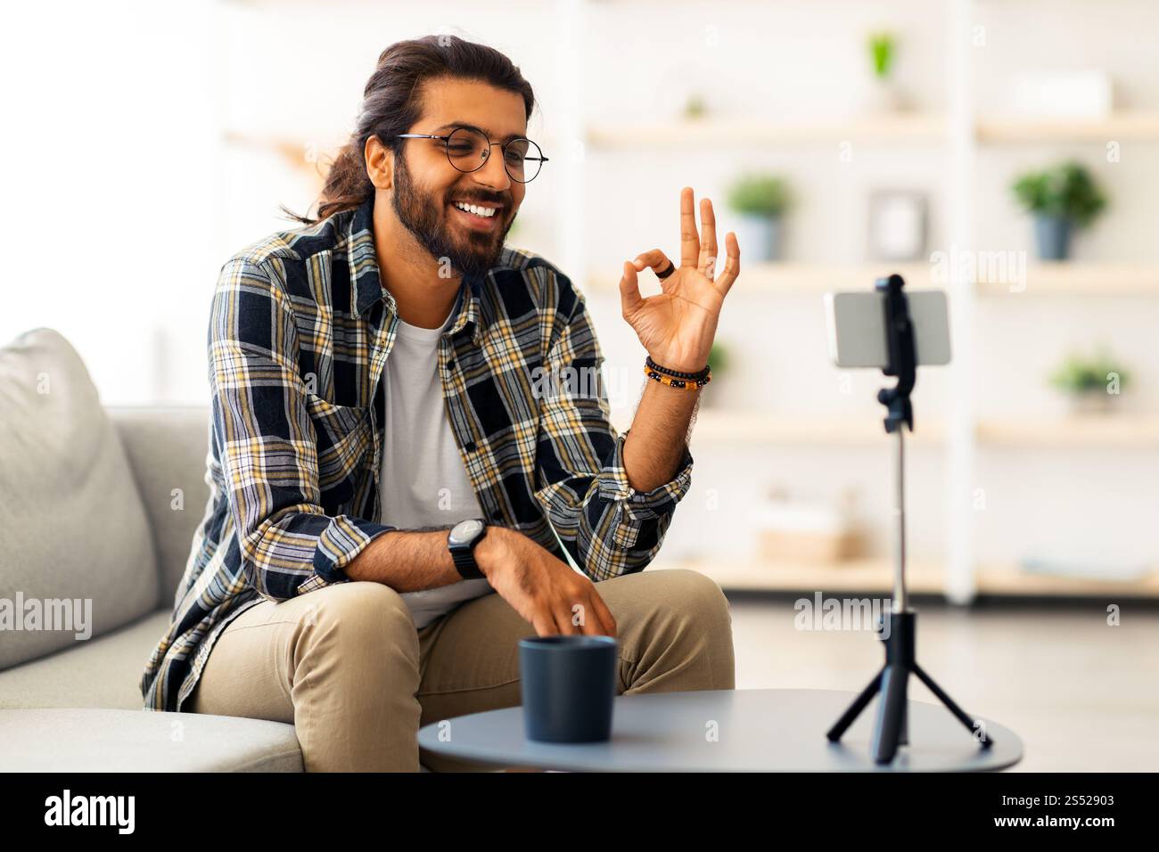 Cheerful indian guy with glasses blogger streaming from home Stock Photo