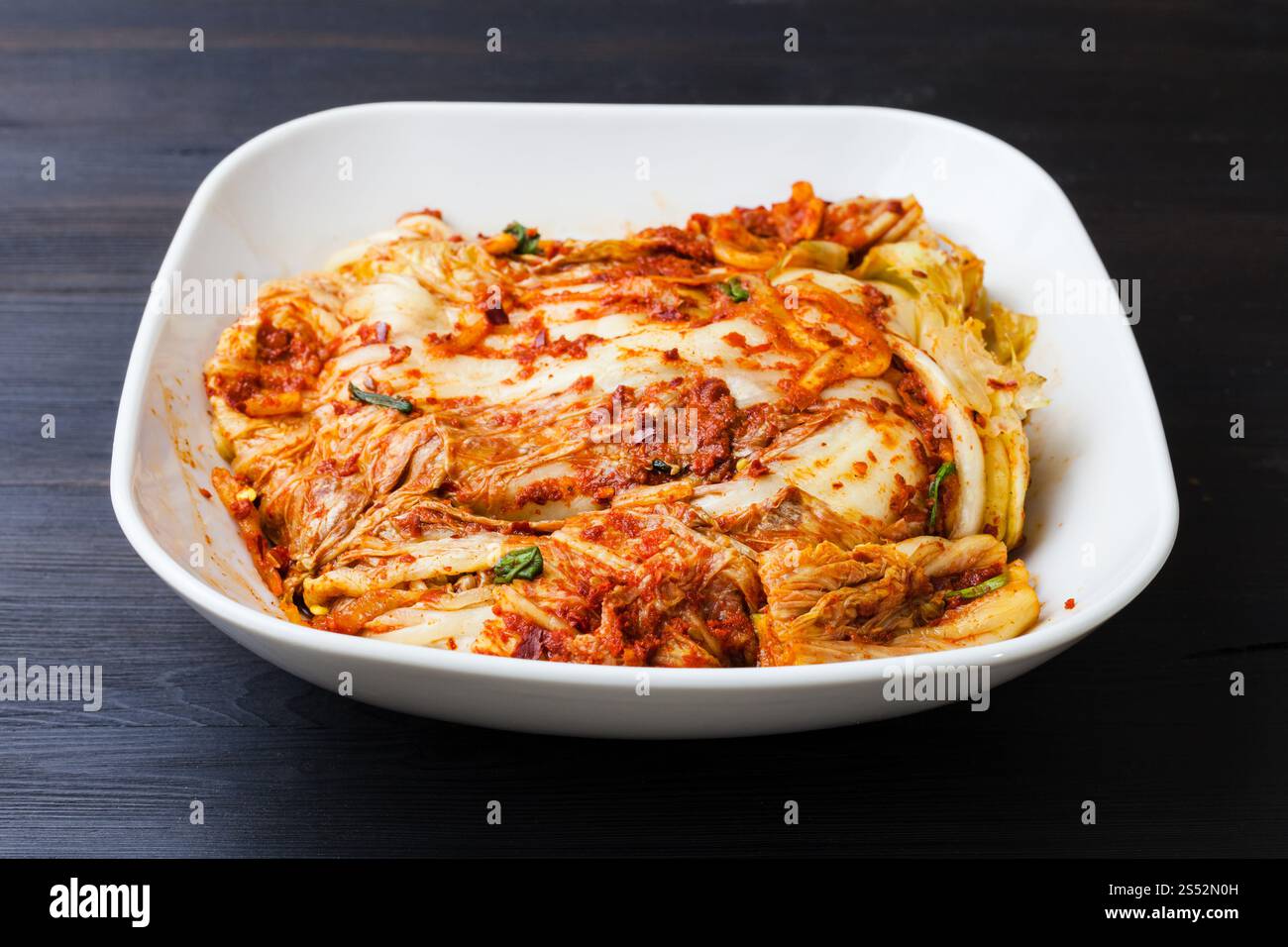 korean cuisine - kimchi appetizer (spice nappa cabbage) in white bowl on dark brown wooden board Stock Photo