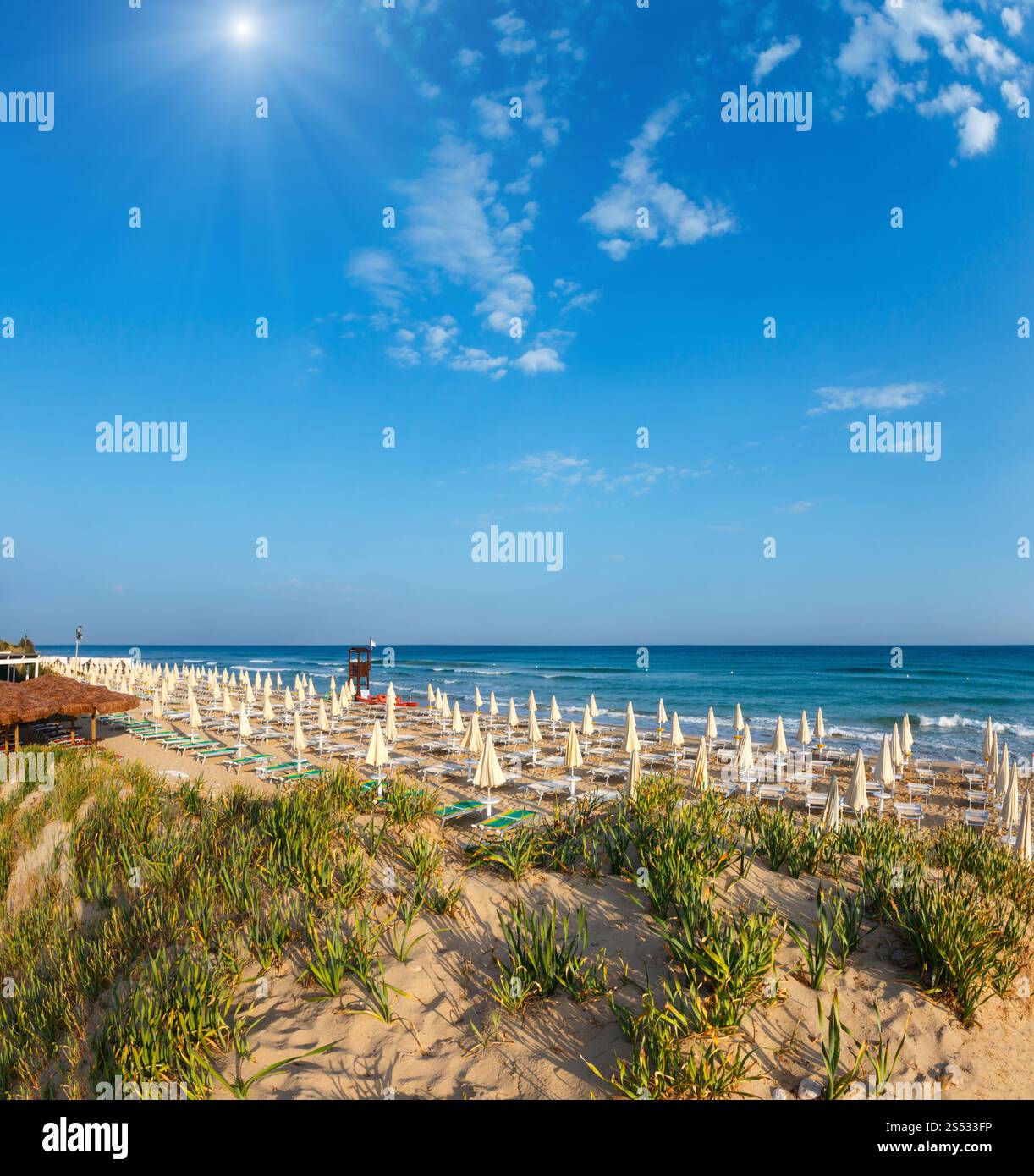 Sunshiny paradise white sandy beach with sunshades and sunbeds (Salento, Puglia, south Italy). The most beautiful sea sandy beach of Apulia. Stock Photo