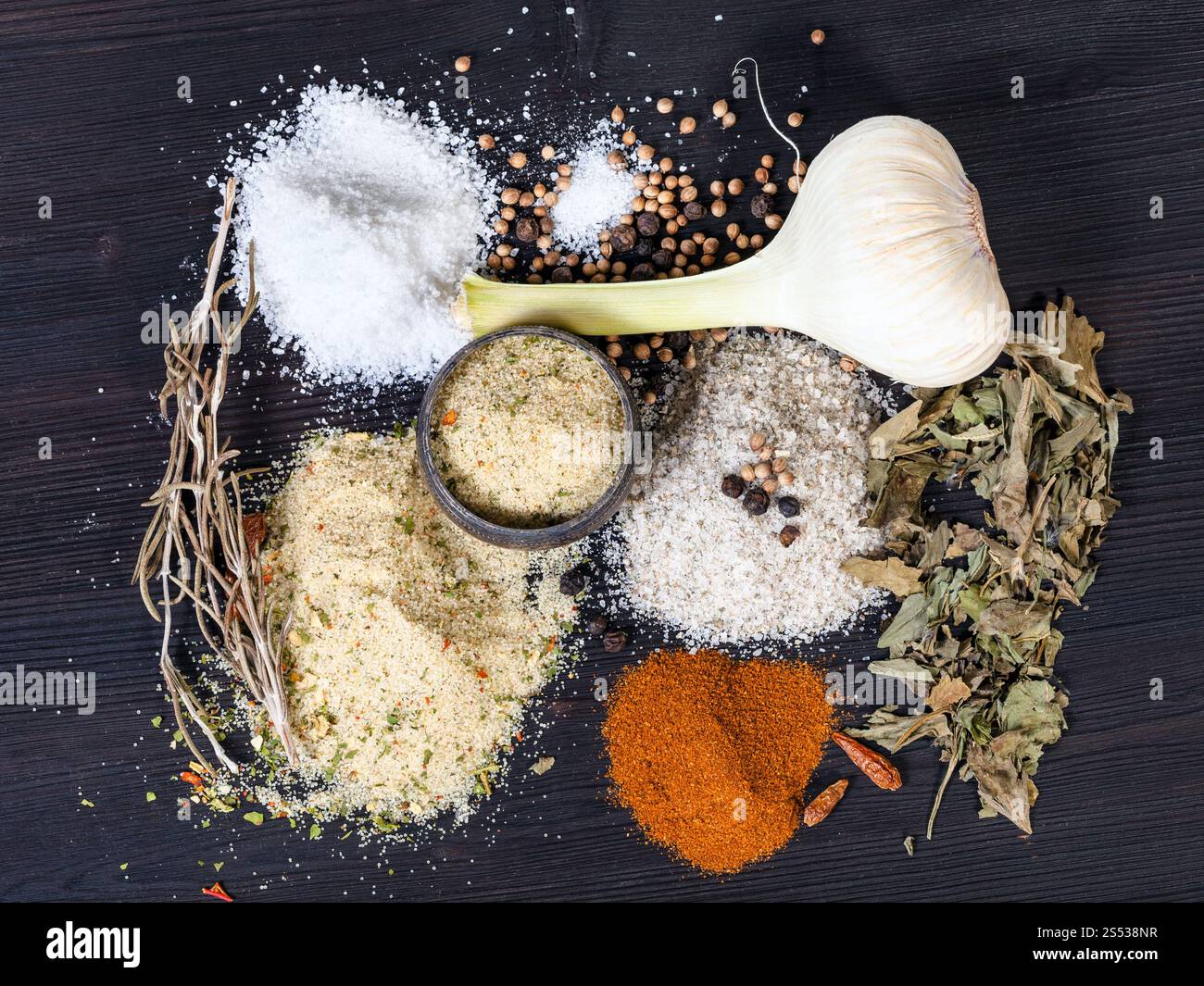 top view of various Seasoned Salts with ingredients on dark brown wooden board Stock Photo