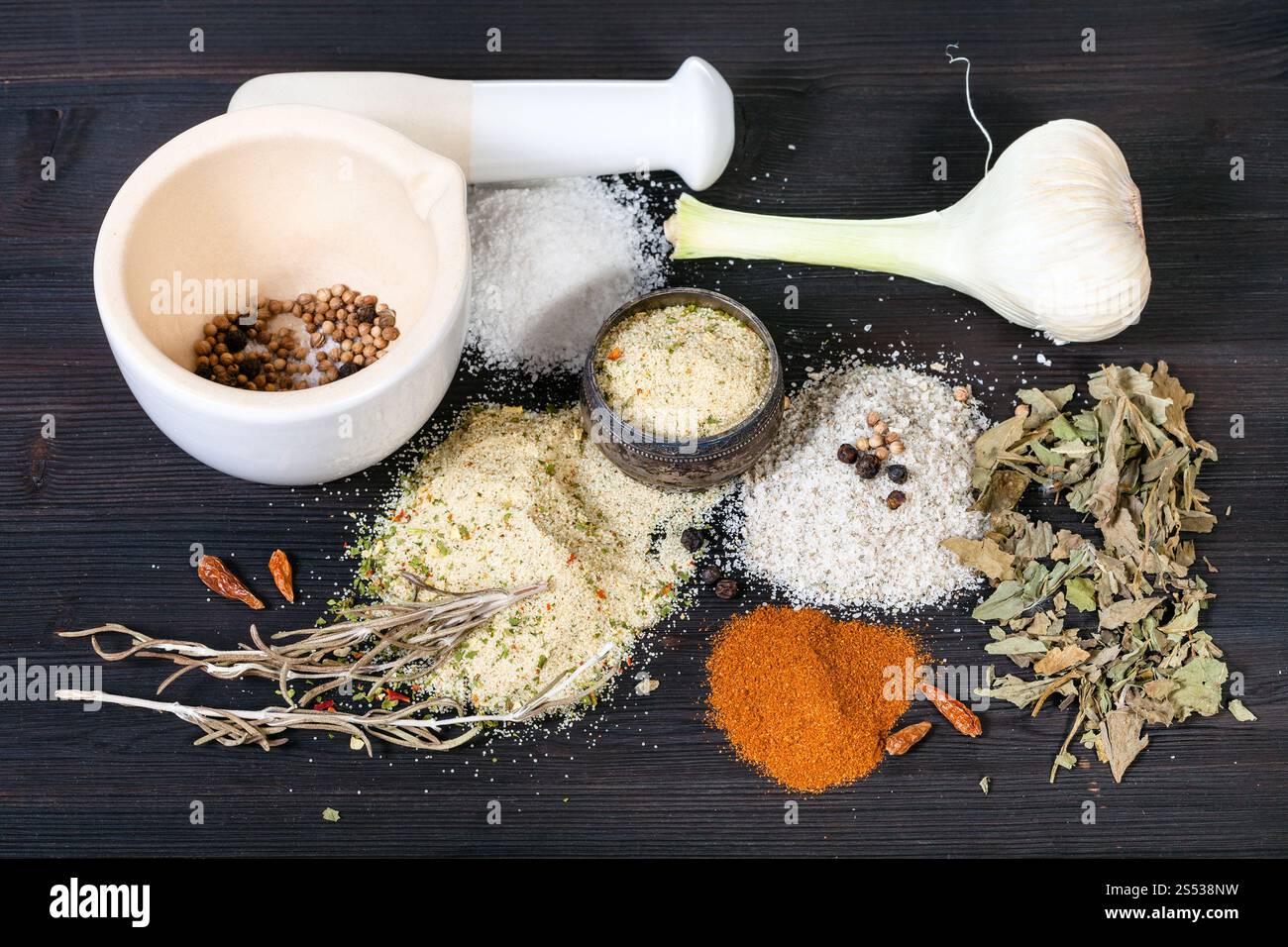 various Seasoned Salts with ingredients and mortar on dark brown wooden board Stock Photo