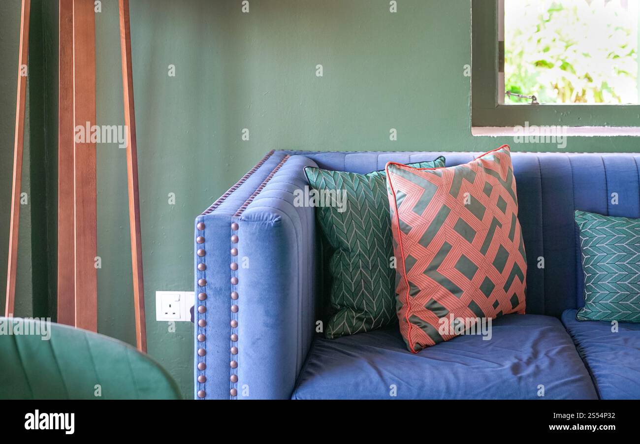 Blue color sofa with colorful throw pillows in a green color room. Stock Photo