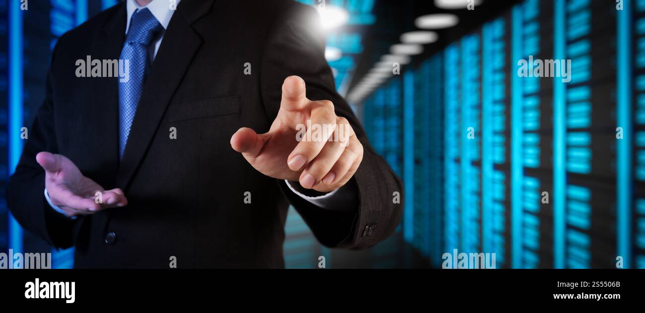 Businessman working with VR wide blank screen computer on server room in background. Stock Photo
