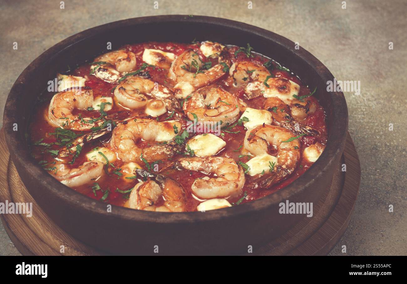 Saganaki with shrimp, in a clay pan, Greek dish, shrimp in tomato sauce ...