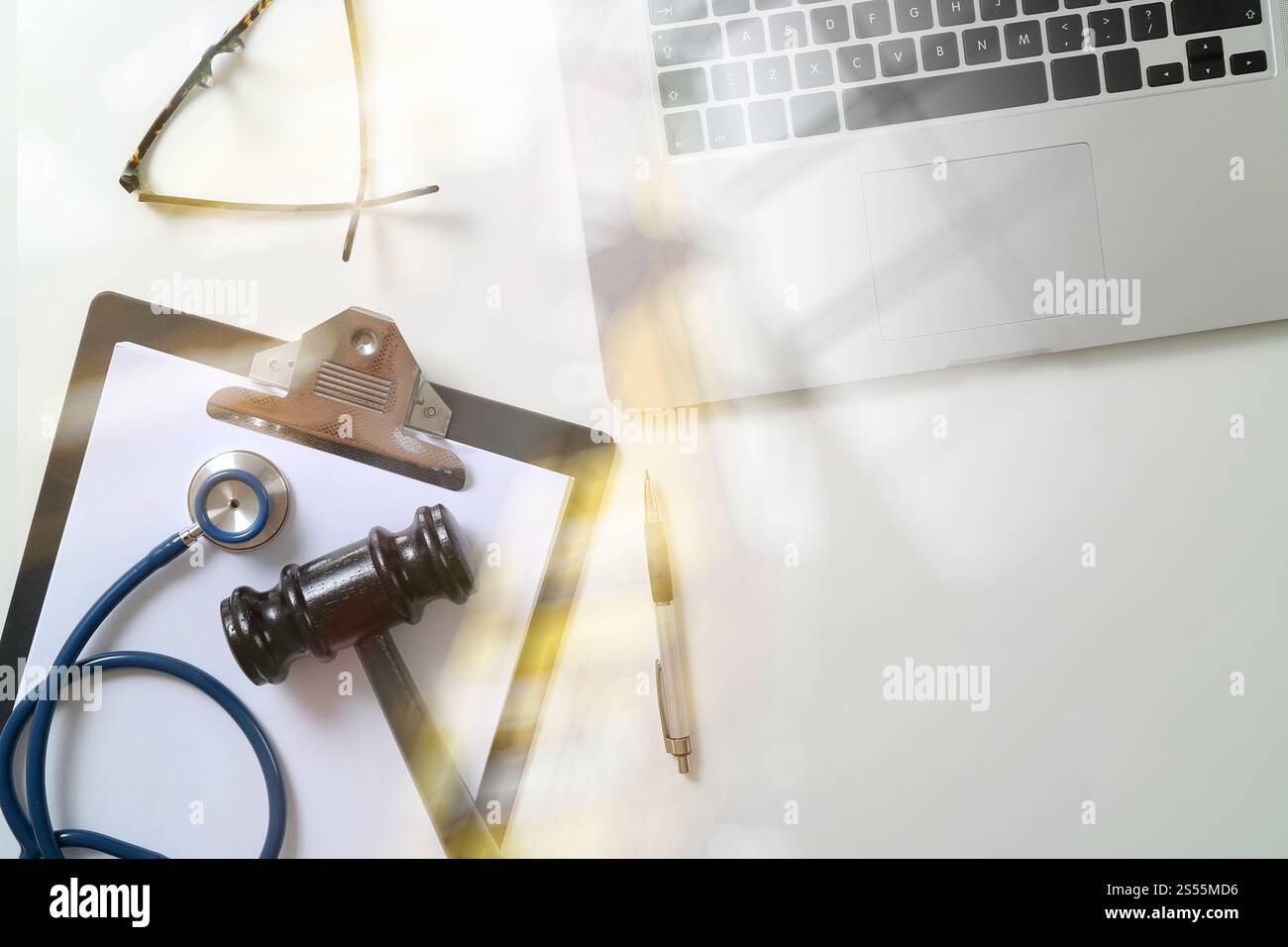 Dark Gavel With Medical Stethoscope near Laptop on white desk In Courtroom concept Stock Photo