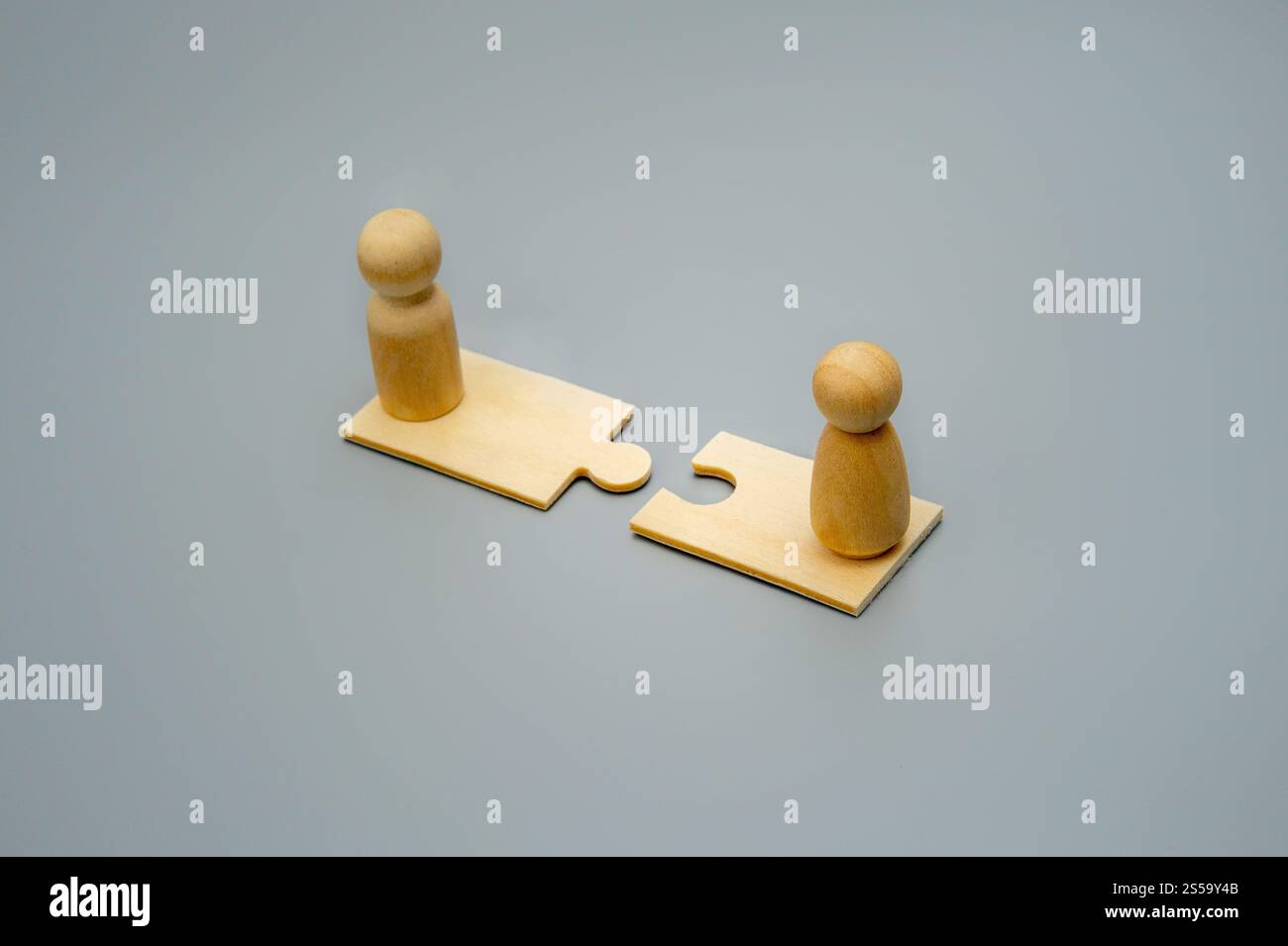 Two wooden figures stand on puzzle pieces facing each other. Connection, teamwork, and collaboration concept. Stock Photo