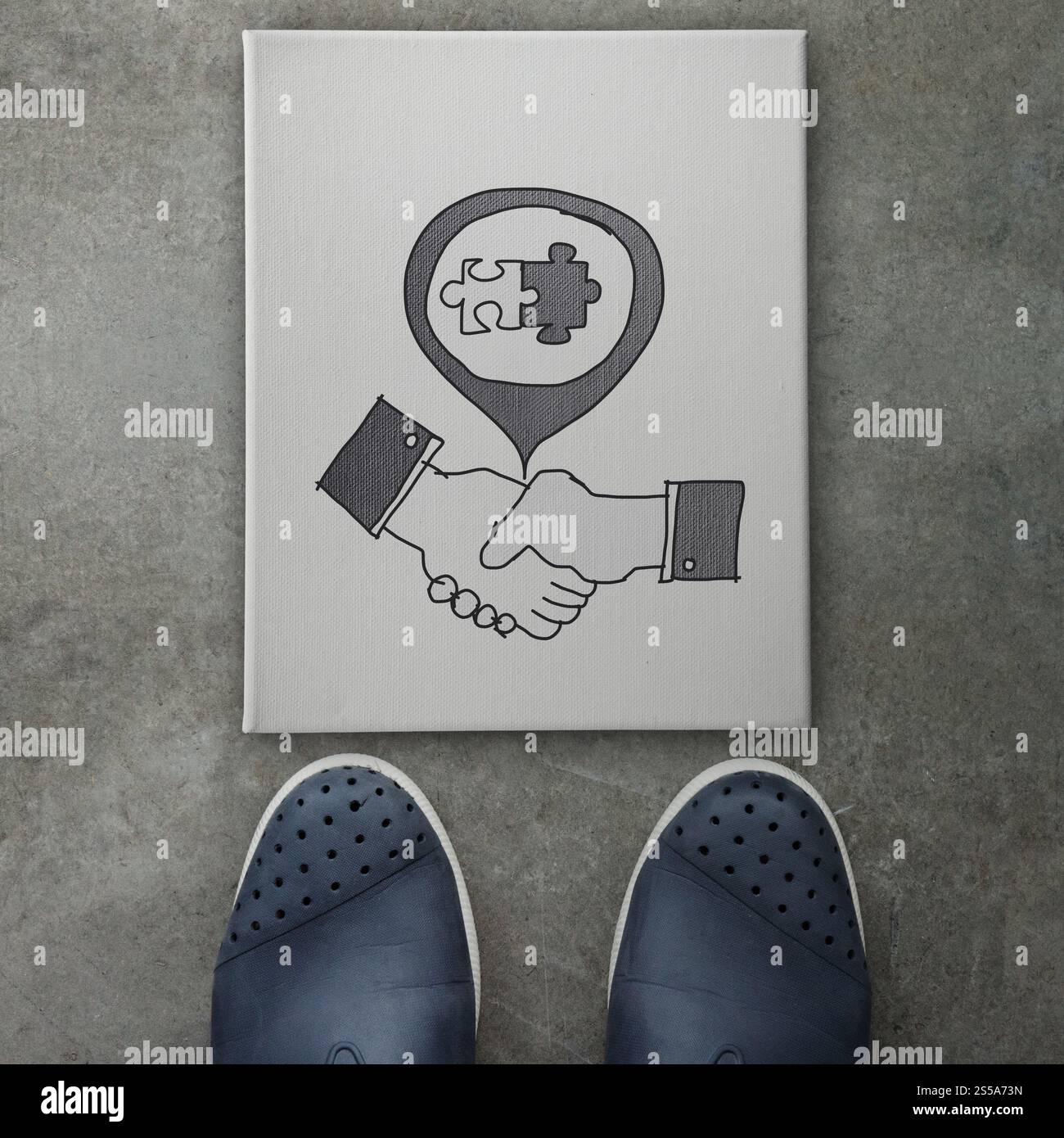 hand drawn handshake signon canvas board on front of business man feet ...