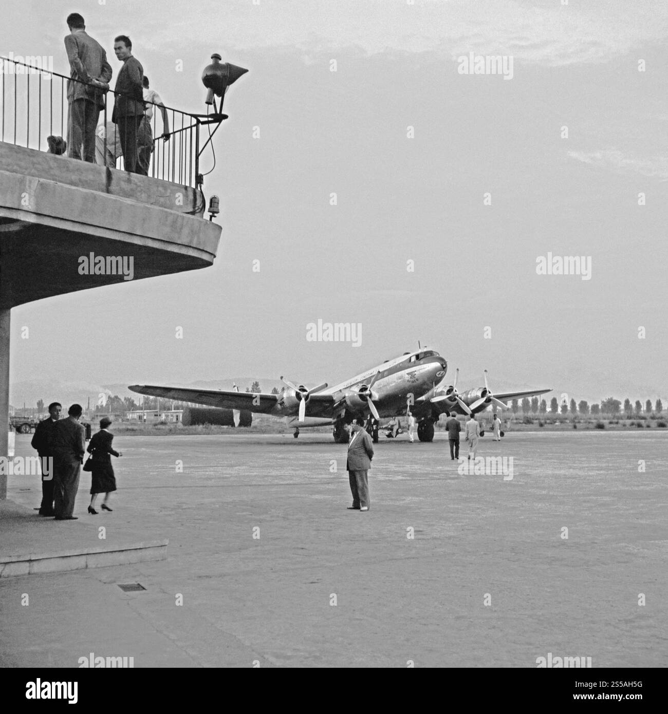 Passengers make their way from the terminal to board a plane at the Josep Tarradellas Barcelona–El Prat Airport, Barcelona, Spain in 1955. They are headed for a four-engined propellor airliner of Aviación y Comercio (Aviaco or AYC), a Spanish airline founded in 1948. and Madrid. Josep Tarradellas Barcelona–El Prat Airport began operations in the late 1940s. Stock Photo