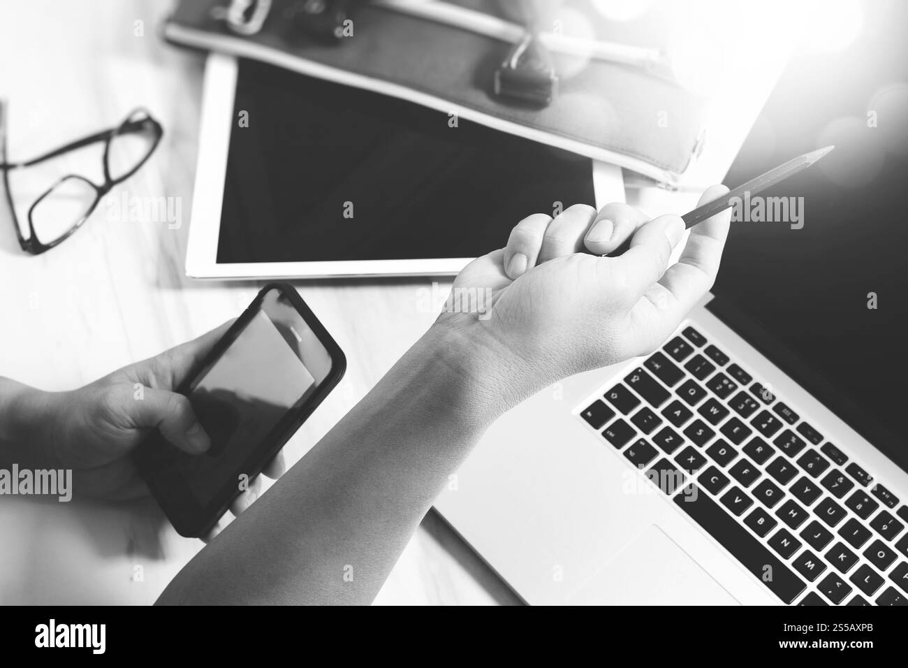 businessman hand working with digital tablet computer and smart phone and laptop computer with business bag on marble desk as concept. Top view, black Stock Photo