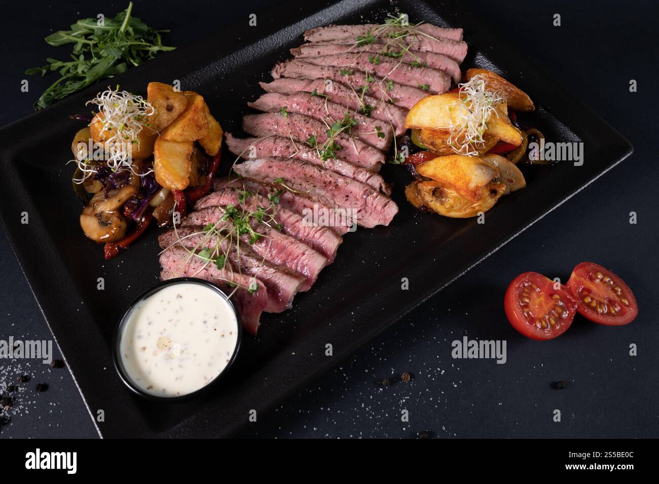 Overhead view of sliced meat with fried potatoes, onions, tomatoes ...