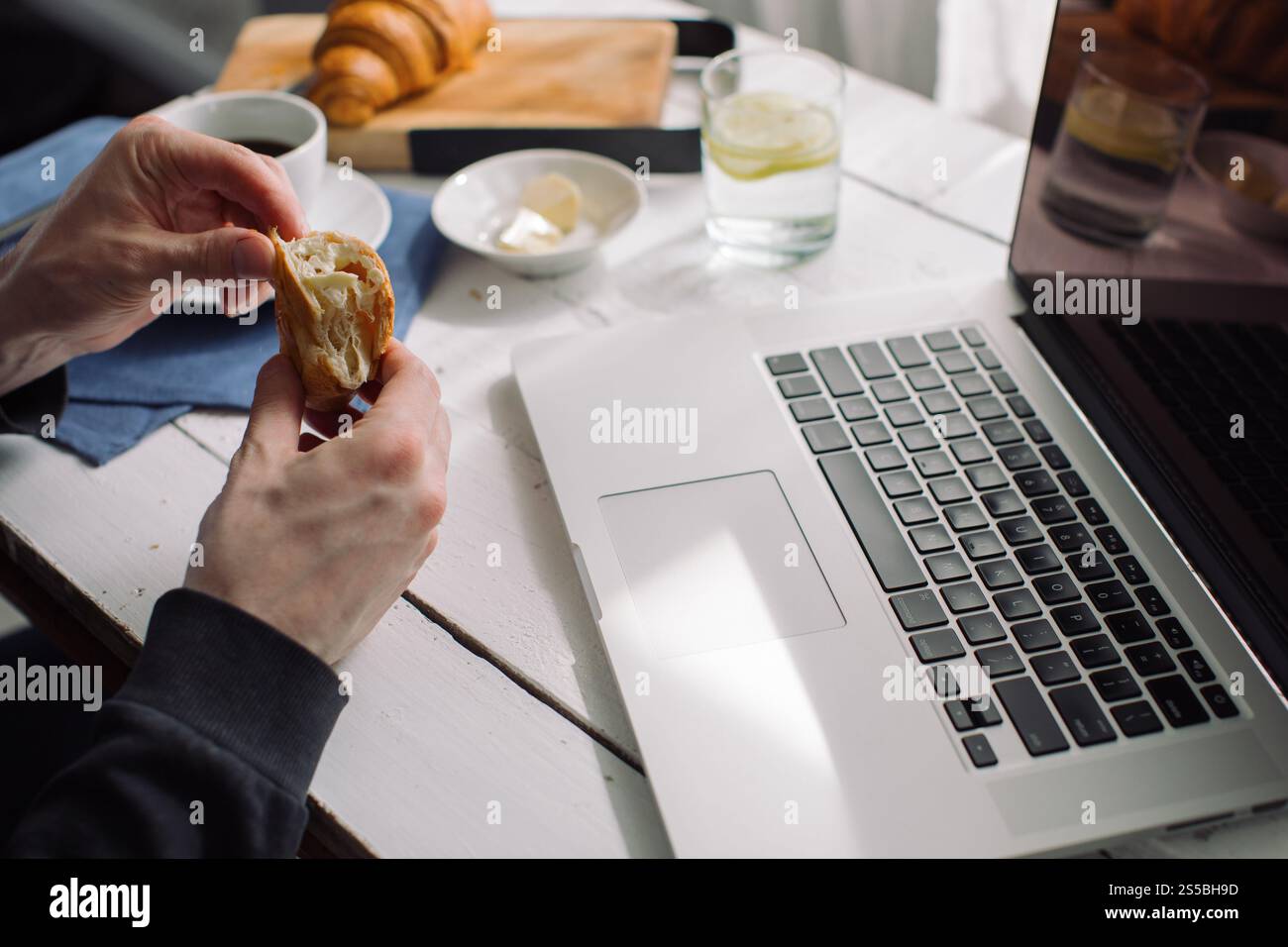 Close-up of a man sitting in front of a laptop computer eating a ...