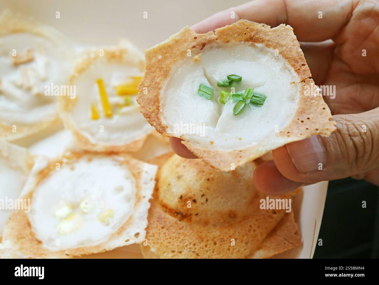Hand Picking a Kanom Krok Spring Onion Topping, Thai coconut milk pancake which one of the popular street food in Thailand Stock Photo