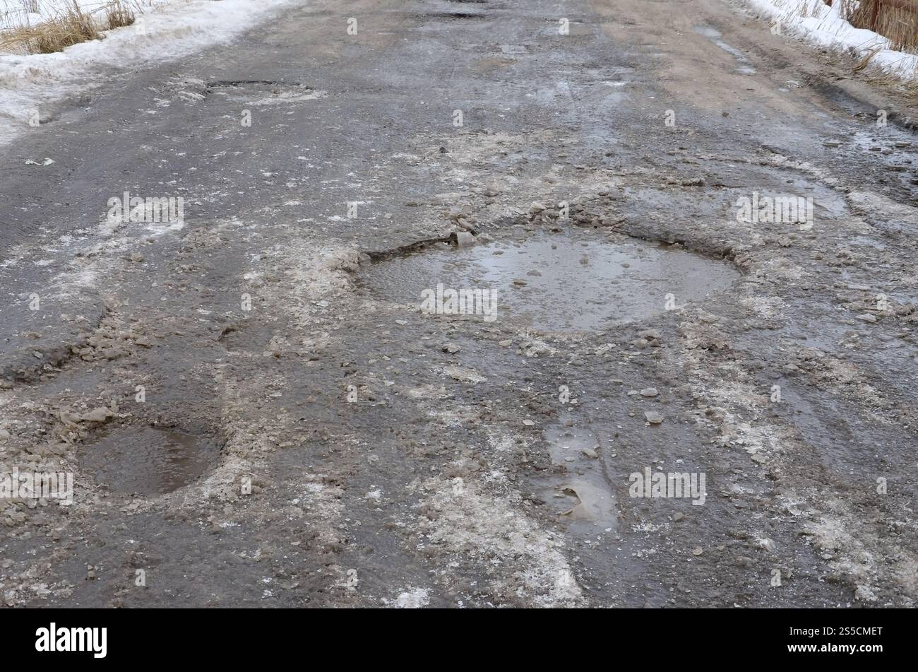 Freezing Roard Condition Damaged asphalt road with potholes caused by freezing and thawing ...