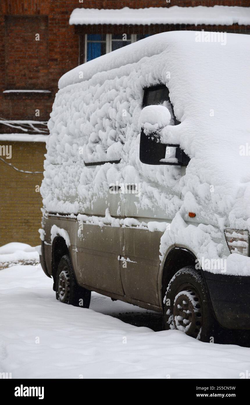 Fragment of the car under a layer of snow after a heavy snowfall. The body of the car is covered with white snow Stock Photo