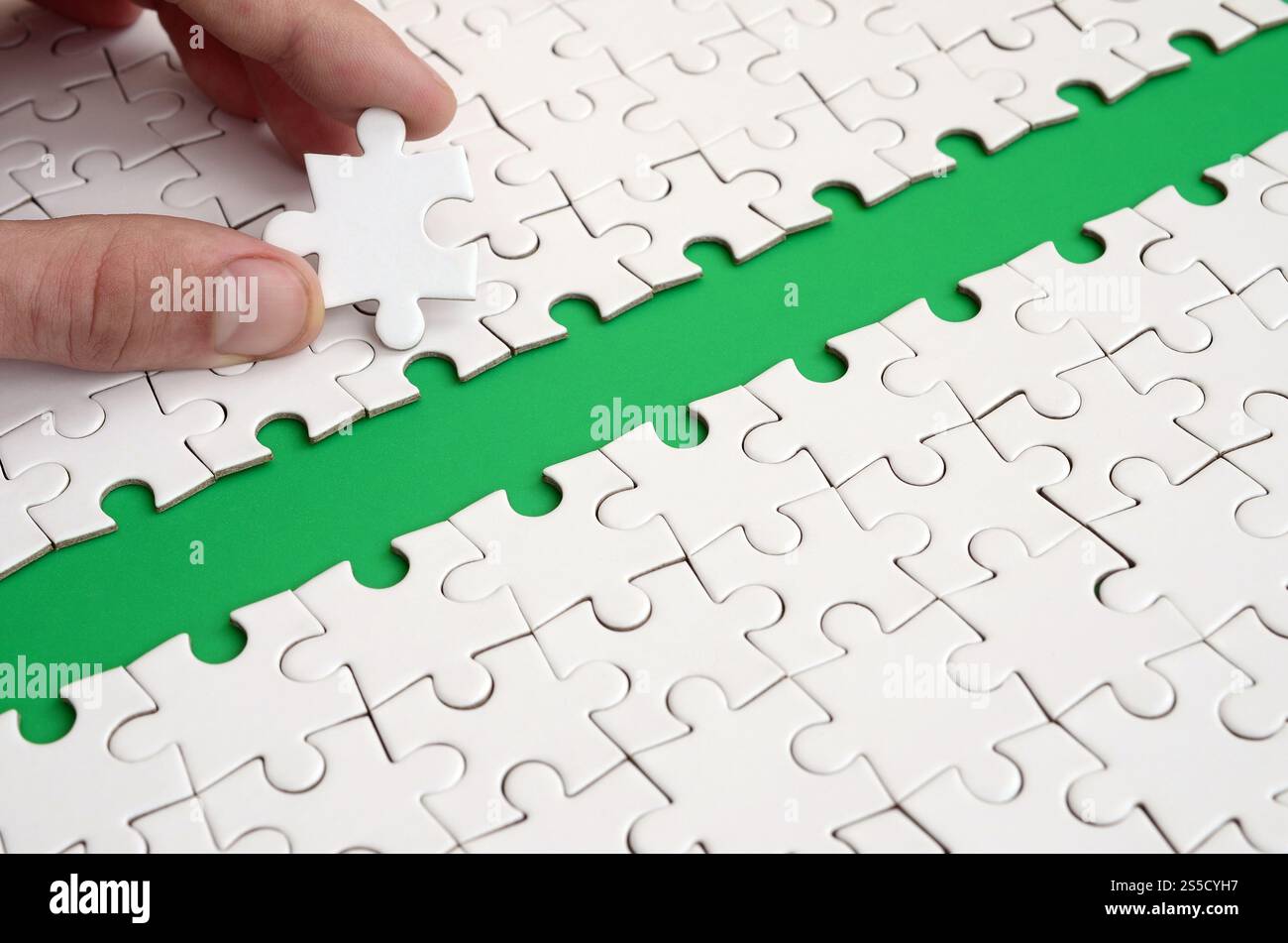 The human hand paves the way to the surface of the jigsaw puzzle The human hand paves the way to the surface of the jigsaw puzzle