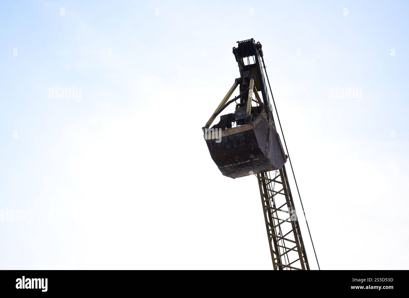 Old yellow mechanical clamshell grab on blue sky background Stock Photo