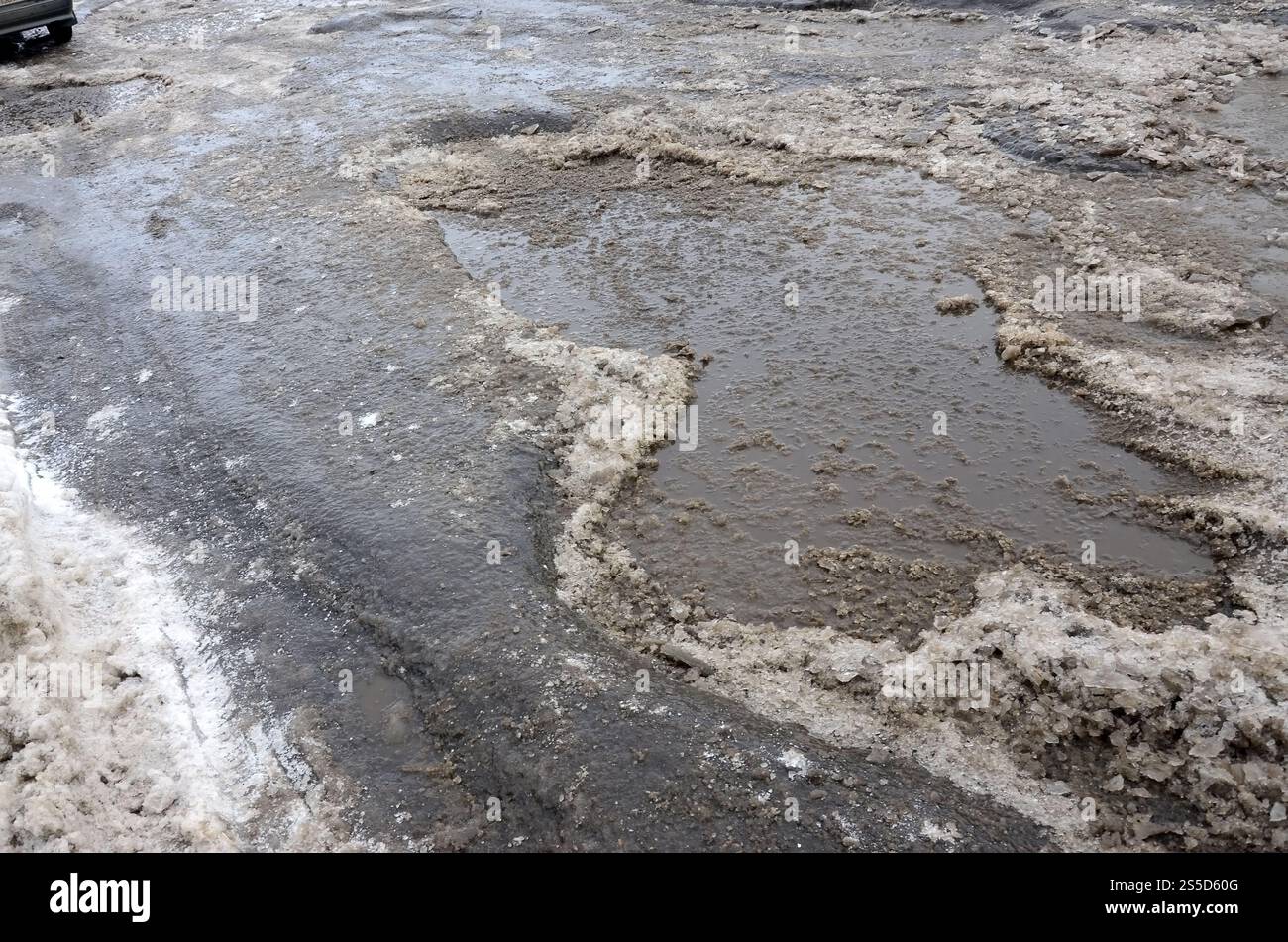 Freezing Roard Condition Damaged asphalt road with potholes caused by freezing and thawing ...