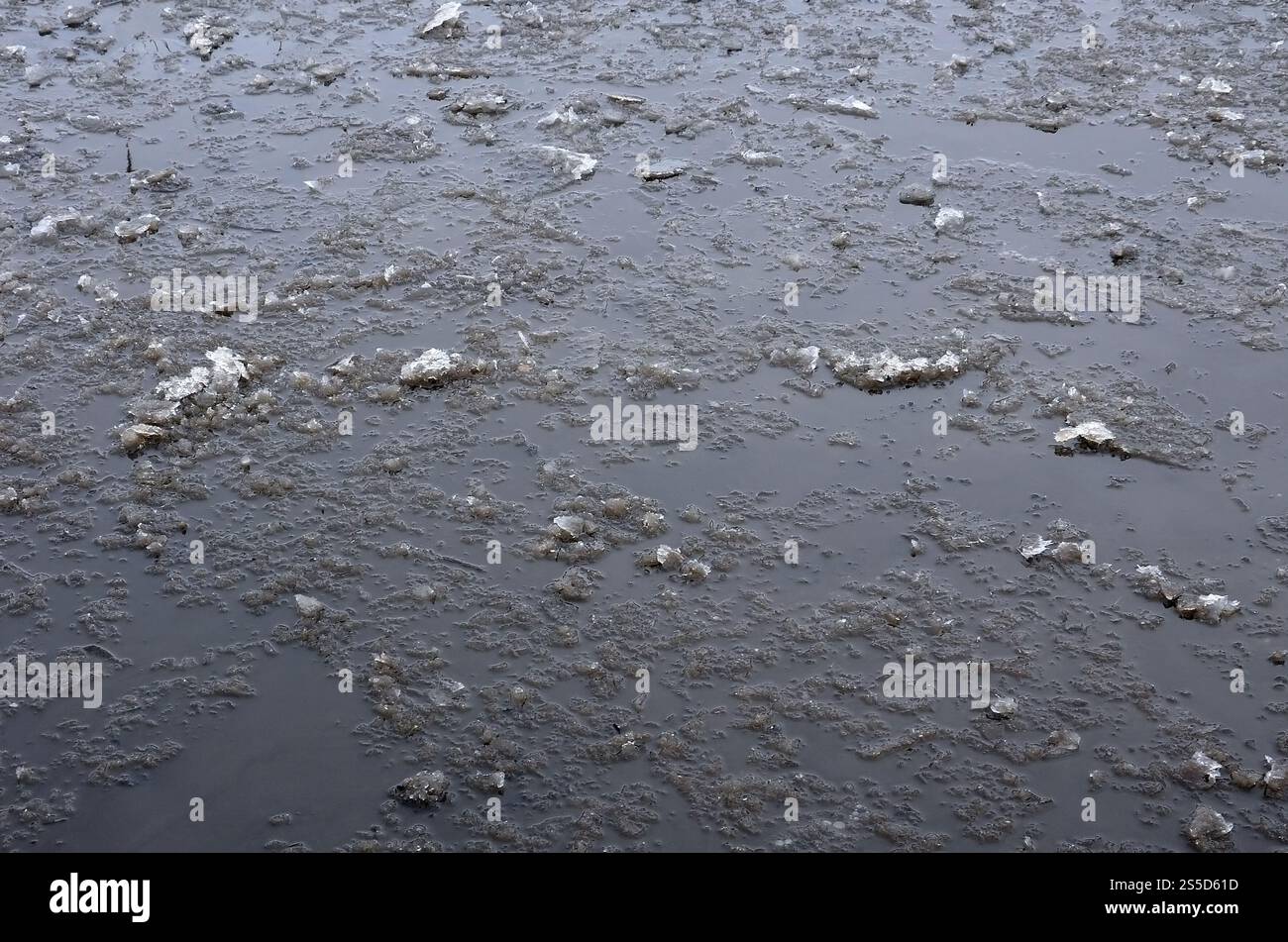 Freezing Roard Condition Damaged asphalt road with potholes, filled with water with ice, caused ...