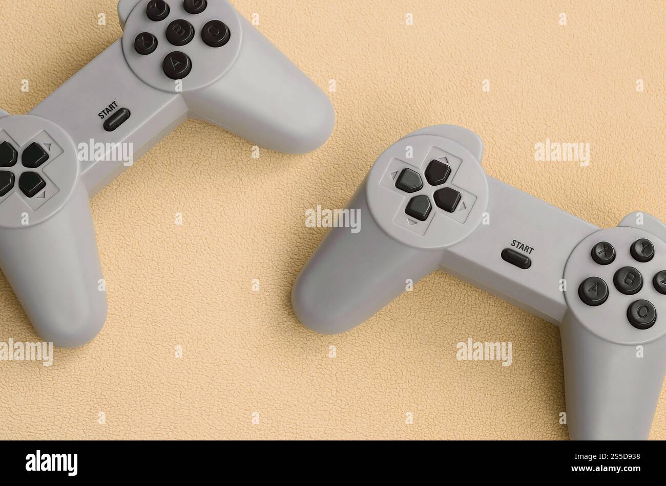 Playing games concept. Two pad joysticks lies on the blanket of furry orange fleece fabric. Controllers for video games on a background texture of Stock Photo