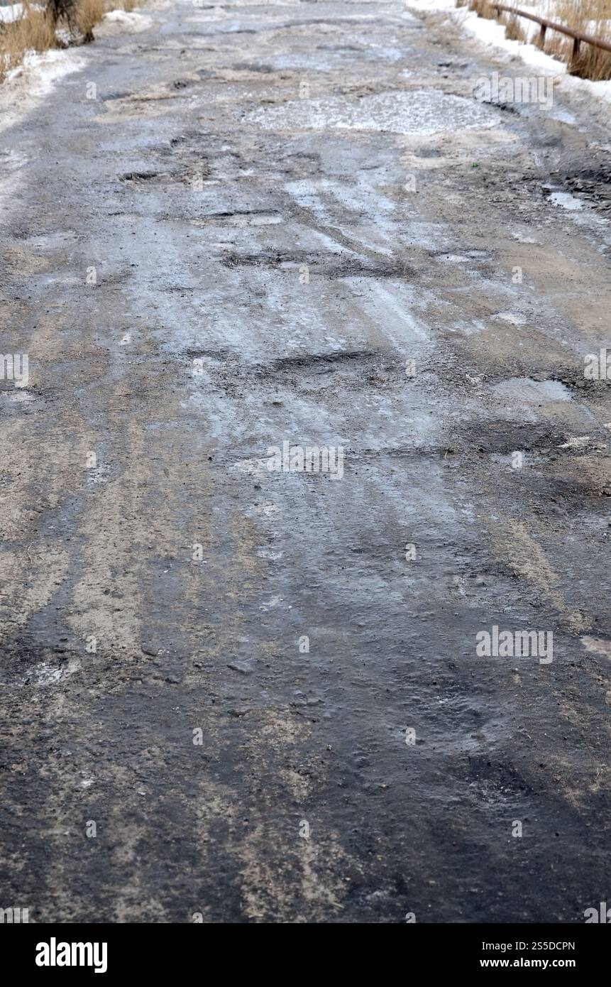 Freezing Roard Condition Damaged asphalt road with potholes caused by freezing and thawing ...
