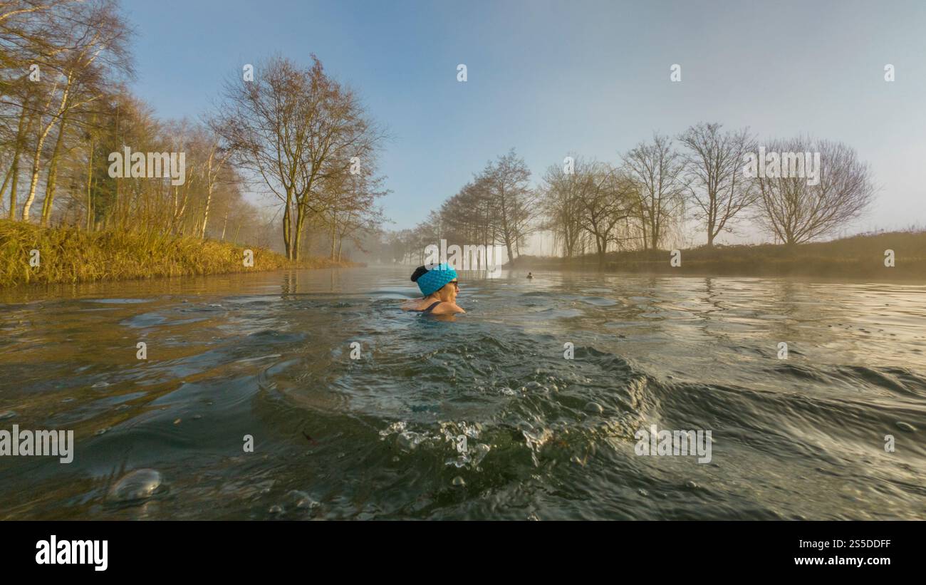 Lone female Wild Swimming at first light on a cold misty winter day. UK Stock Photo