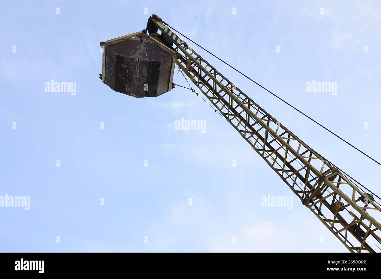 Old yellow mechanical clamshell grab on blue sky background Stock Photo