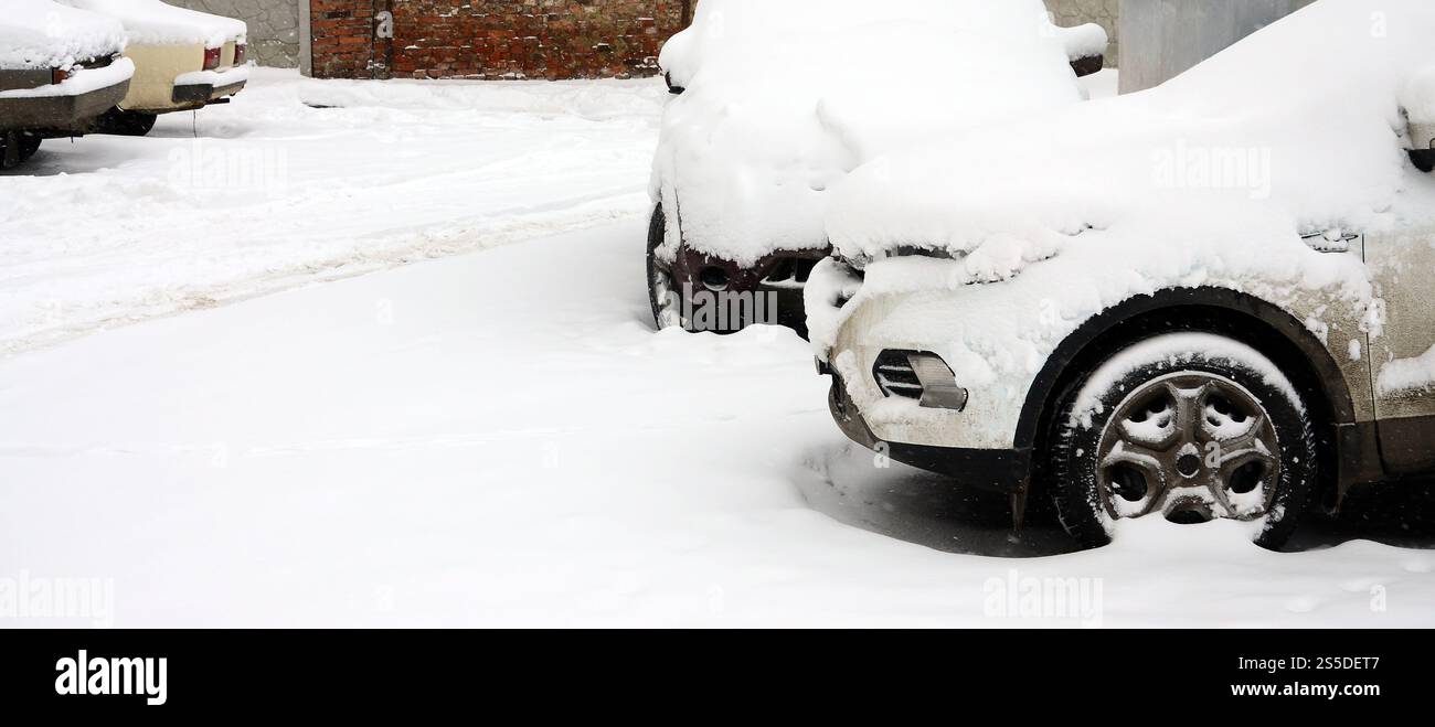 Fragment of the car under a layer of snow after a heavy snowfall. The body of the car is covered with white snow Stock Photo