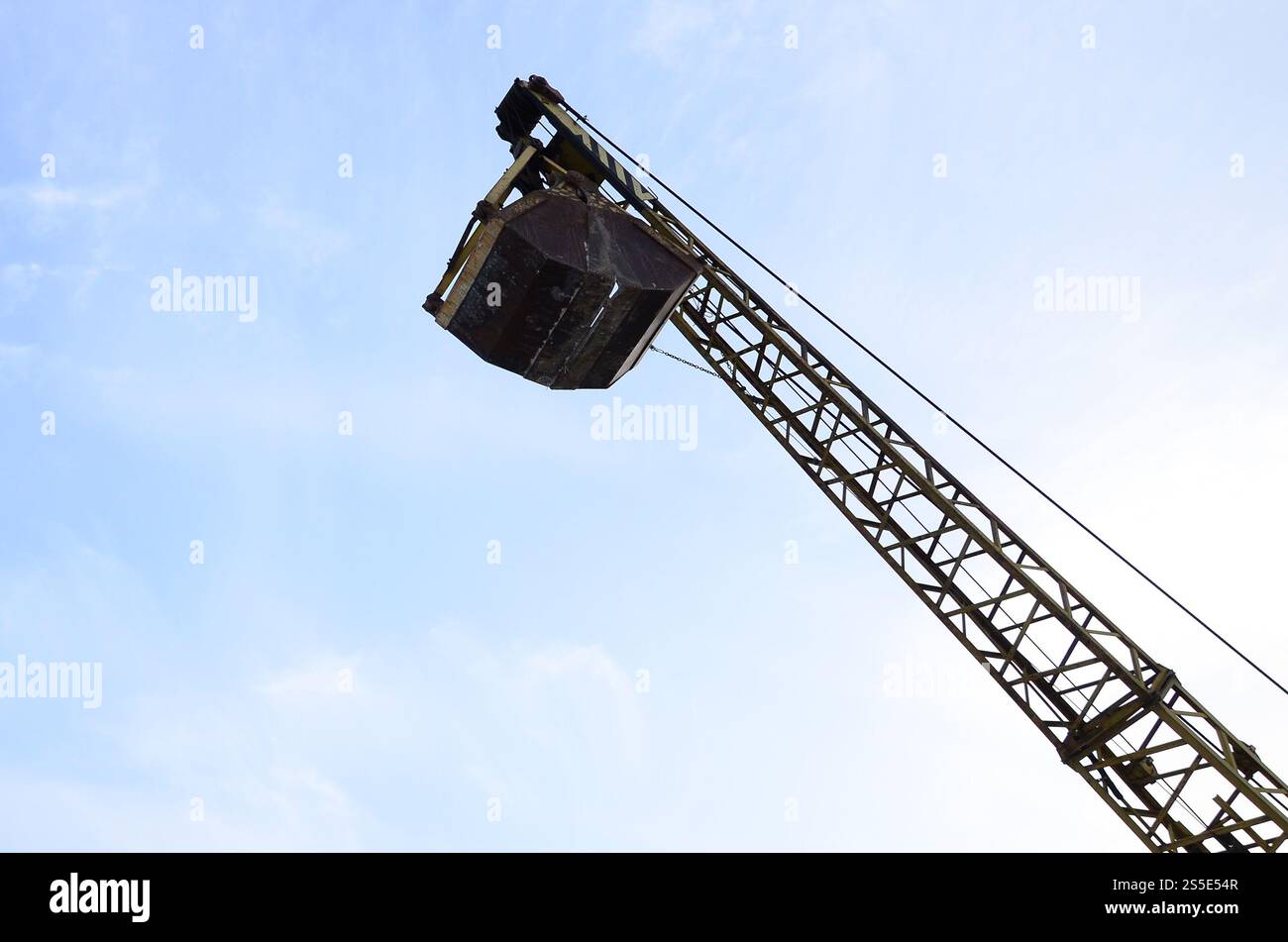 Old yellow mechanical clamshell grab on blue sky background Stock Photo